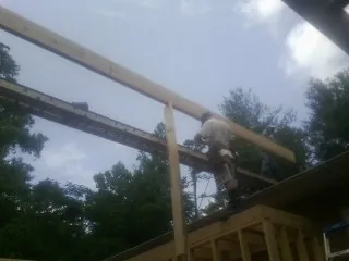 Carpenter setting a ridge beam over a new addition frame — Ice Dam Removal by Roofing Brothers in Waynoka