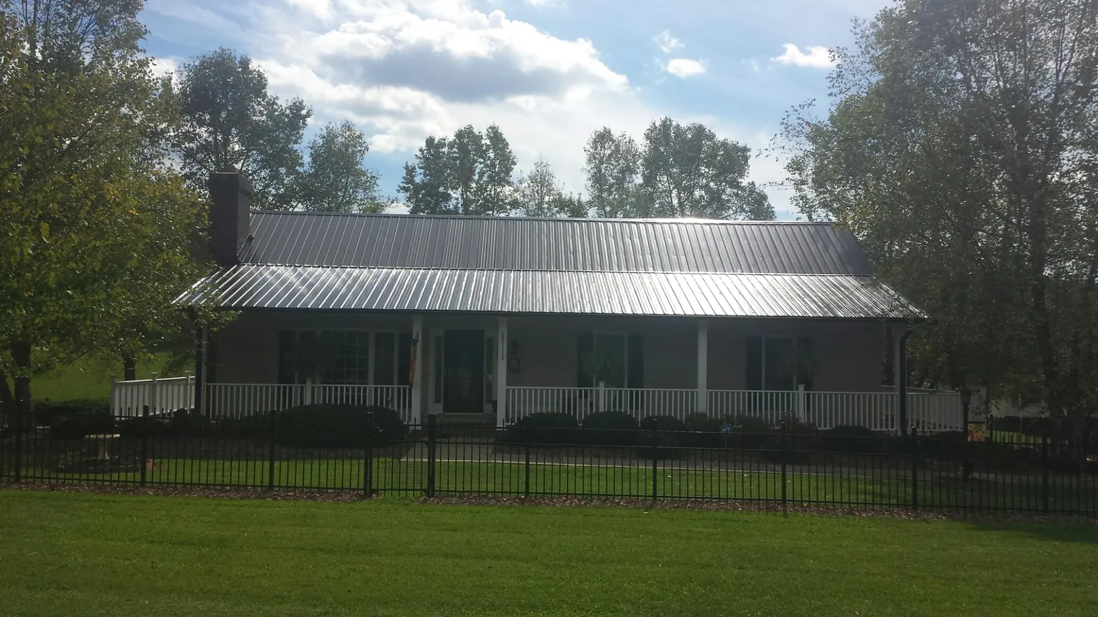 Gray metal roof on a brick ranch with a full width front porch — Gutter Guard Installation work by our crew in Waynoka