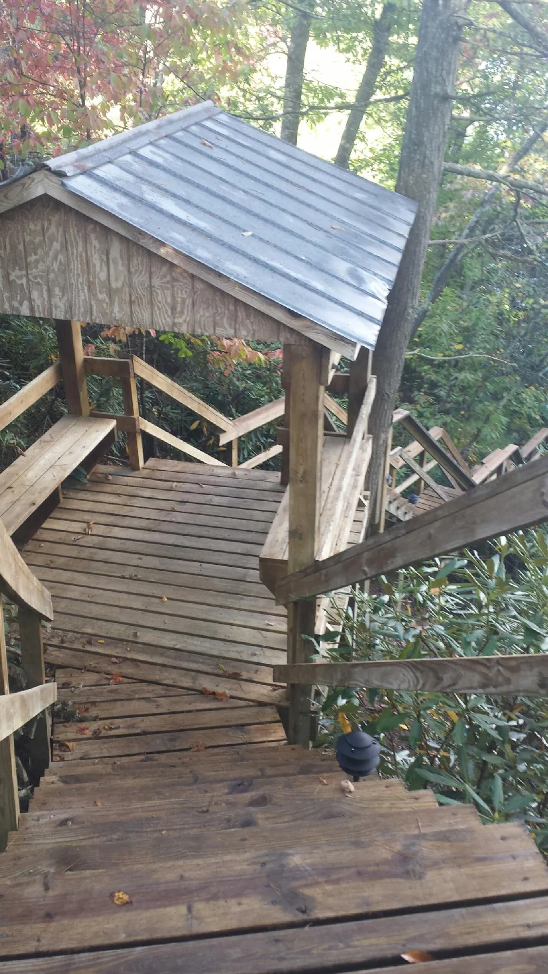 Metal roofed shelter over wooden steps on a wooded walkway — Skylight Repair & Installation work by our crew in Waynoka