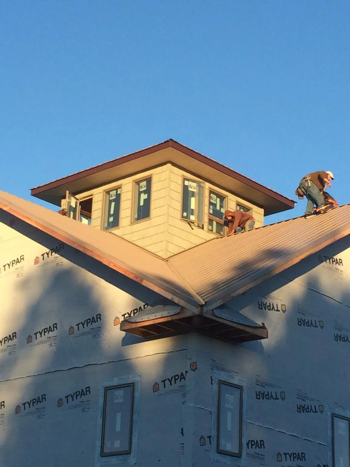 Roofers working around a rooftop cupola on a new metal roof at sunset — Roof Waterproofing in Waynoka by Roofing Brothers